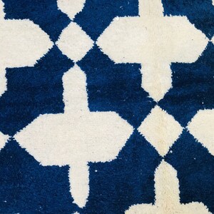 May include: A white and blue geometric patterned rug with a Moroccan design. The rug has a soft, fluffy texture.