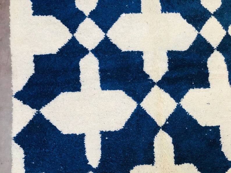 May include: A white and blue geometric patterned rug with a Moroccan design. The rug has a soft, fluffy texture.