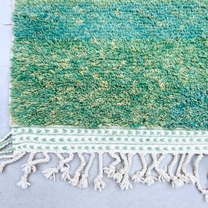 K&ouml;nnte beinhalten: Ein gr&uuml;ner und blauer Shaggy-Teppich mit einem wei&szlig;en Fransenrand. Der Teppich hat einen subtilen Ombre-Effekt, der von einem dunkleren Gr&uuml;n zu einem helleren Blau &uuml;bergeht.