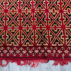 K&ouml;nnte beinhalten: Ein roter, schwarzer, gr&uuml;ner und gelber Teppich mit geometrischem Muster. Der Teppich hat einen Fransenrand.