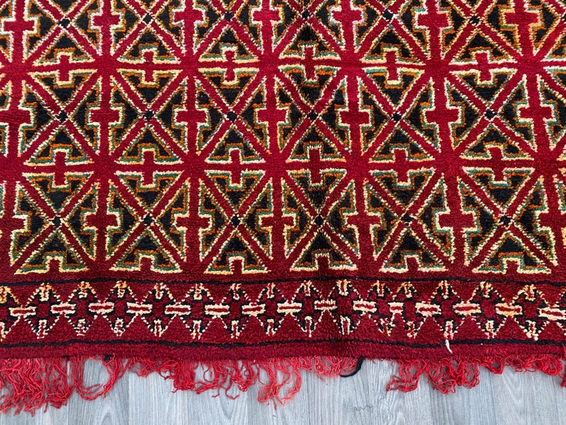 K&ouml;nnte beinhalten: Ein roter, schwarzer, gr&uuml;ner und gelber Teppich mit geometrischem Muster. Der Teppich hat einen Fransenrand.