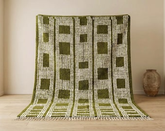 May include: A green and white patterned rug with a geometric design. The rug features a repeating pattern of vertical stripes and square blocks. The rug has a fringe along the bottom edge and is displayed against a neutral background.