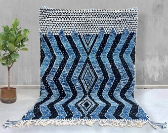 Könnte beinhalten: Blau-weißer Teppich mit geometrischem Muster. Der Teppich hat einen Fransenrand.