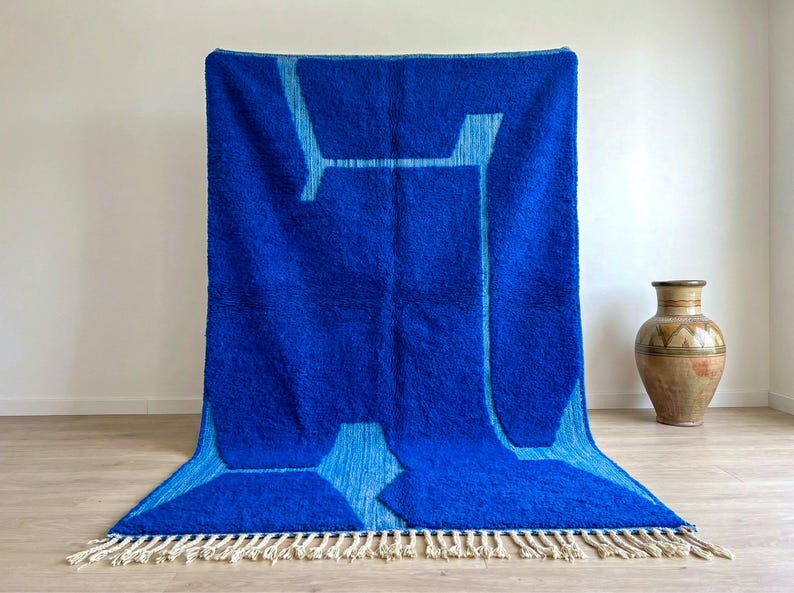 Handmade blue Beni Ourain Moroccan rug displayed vertically with abstract Berber pattern and wool fringe