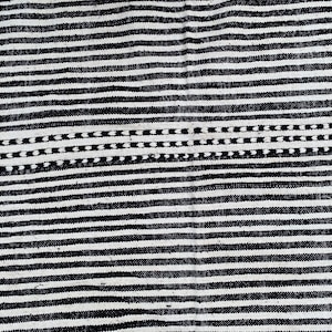 Wool Moroccan rug handwoven with alternating black and white stripes running vertically (see photos). Authentic Berber craftsmanship is reflected in its balanced design and fringed finish. This durable carpet complements Scandinavian-inspired interiors, bohemian spaces, or modern homes, providing cultural authenticity, texture, and timeless Moroccan artistry to any room.