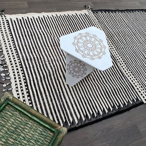 Authentic Moroccan rug with striking vertical stripes in black and white wool (see photos). Each line is carefully handwoven by Berber artisans, creating a minimalist yet bold design. The fringed borders highlight its traditional charm, making it ideal for modern living spaces, bohemian homes, or minimalist interiors in need of texture and cultural artistry.