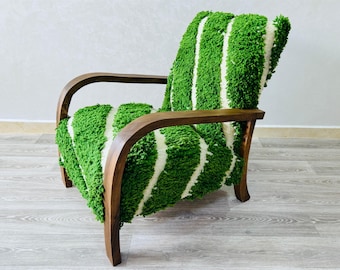 Puede incluir: Un sillón retro con estructura de madera y asiento y respaldo cubiertos con tela de felpa a rayas verdes y blancas. La silla tiene reposabrazos curvos y un diseño cómodo.