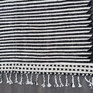 Authentic Moroccan wool rug in a striped pattern, alternating black and white bands that create a bold linear effect (see photos). Finished with fringes, this handmade Berber carpet combines cultural craftsmanship with modern minimalist appeal. A versatile piece that suits bohemian, eclectic, or Scandinavian-inspired homes, offering both comfort and timeless Moroccan artistry.