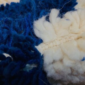 May include: Close-up of a blue and white fluffy rug with a textured surface. The rug is made of soft, fuzzy fibres.