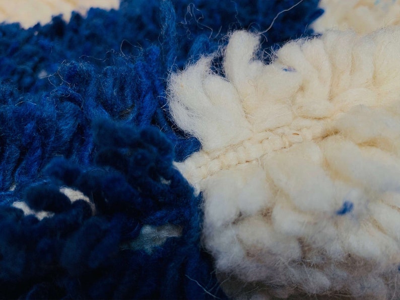 May include: Close-up of a blue and white fluffy rug with a textured surface. The rug is made of soft, fuzzy fibres.