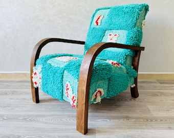 May include: A turquoise armchair with a patchwork design and wooden arms. The chair has a unique, textured fabric with red and white accents.