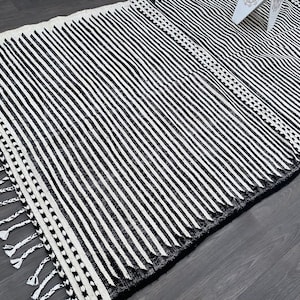 Minimalist Moroccan rug handmade in wool, showcasing vertical black and white stripes (see photos). Finished with fringes, this authentic Berber carpet reflects Moroccan tradition while adapting to modern decor. Perfect for bohemian living rooms, cozy bedrooms, or chic apartments, it adds warmth, elegance, and artisanal heritage to your interior space.