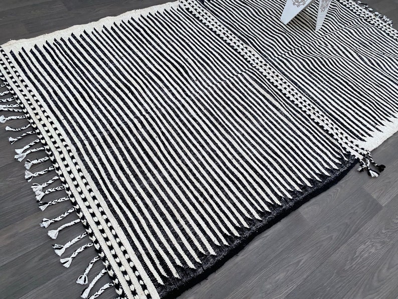 Minimalist Moroccan rug handmade in wool, showcasing vertical black and white stripes (see photos). Finished with fringes, this authentic Berber carpet reflects Moroccan tradition while adapting to modern decor. Perfect for bohemian living rooms, cozy bedrooms, or chic apartments, it adds warmth, elegance, and artisanal heritage to your interior space.