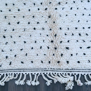May include: White and black patterned rug with fringe. The rug has a white background with black dots and a black and white border.