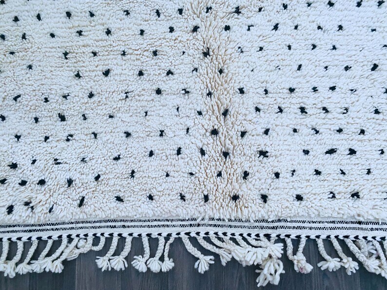 May include: White and black patterned rug with fringe. The rug has a white background with black dots and a black and white border.