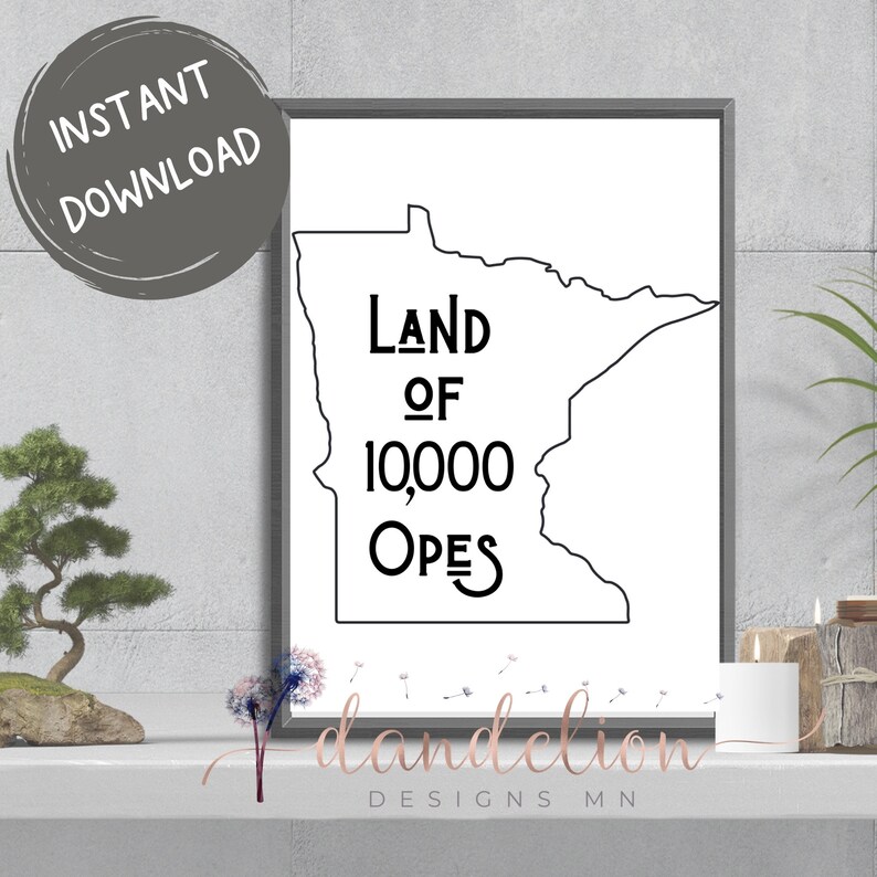 May include: A framed black and white print displaying the outline of Minnesota, with the text "Land of 10,000 Opes". The phrase is centrally positioned within the state's shape. The words "Instant Download" are in a grey circle in the upper left corner.