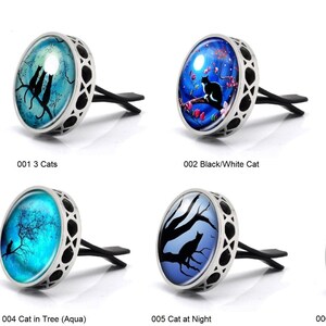 May include: Six different car air fresheners with various cat designs. Each air freshener is silver with a round glass insert featuring a different cat image. The images include three cats, a black and white cat, a cat in a tree, a cat in a tree with an aqua background, a cat at night, and a cat in a tree with a beige background.
