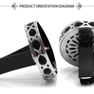 May include: Silver car air freshener with a geometric design. The air freshener has a black clip to attach to a car vent.
