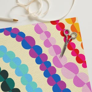 May include: A colourful wrapping paper design with a repeating pattern of half circles in shades of green, blue, teal, purple, pink, red, and orange. The background is a light yellow.