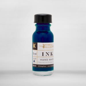 May include: A 15 ml bottle of blue ink with a gold label that says "INK HAND MADE". The label also includes a feather illustration and the text "Colors may vary from batch to batch".