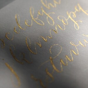 Pu&ograve; includere: Primo piano di una busta bianca con calligrafia dorata che recita "l'amore &egrave; tutto ci&ograve; di cui hai bisogno".