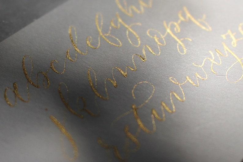 Pu&ograve; includere: Primo piano di una busta bianca con calligrafia dorata che recita "l'amore &egrave; tutto ci&ograve; di cui hai bisogno".