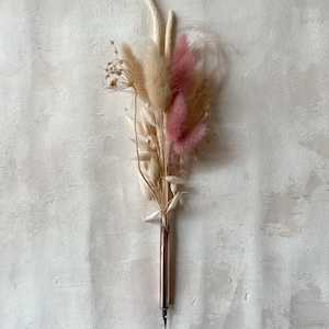 May include: A bouquet of dried pampas grass and pink bunny tail grass with a copper dip pen attached to the bottom.