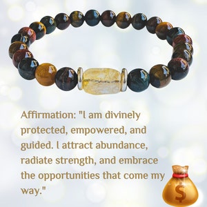 K&ouml;nnte beinhalten: Ein Armband mit Tigerauge-, Rotjaspis- und Goldstone-Perlen. Das Armband hat einen Anh&auml;nger aus klarem Quarzkristall und einen silbernen Akzent. Die Affirmation "Ich bin g&ouml;ttlich besch&uuml;tzt, erm&auml;chtigt und gef&uuml;hrt. Ich ziehe F&uuml;lle an, strahle St&auml;rke aus und umarme die M&ouml;glichkeiten, die mir begegnen." steht unter dem Armband.