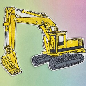 K&ouml;nnte beinhalten: Gestickter Aufn&auml;her mit einem gelben Bagger mit schwarzen und grauen Details. Das Bauger&auml;t ist im Profil dargestellt, mit einem detaillierten Eimer und Ketten. Der Aufn&auml;her hat einen wei&szlig;en Rand und ist vor einem pastellfarbenen Hintergrund platziert.