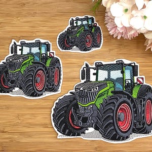 Könnte beinhalten: Drei gestickte Aufnäher mit grünen Traktoren, schwarzen Reifen und roten Felgen. Jeder Aufnäher zeigt ein detailliertes landwirtschaftliches Fahrzeug mit Fahrerkabine, Frontgrill und großen Profilreifen, die mit Garn auf weißem Untergrund gestickt sind.