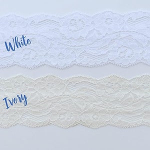 May include: Two samples of lace trim, one white and one ivory. The lace is delicate and has a floral pattern.