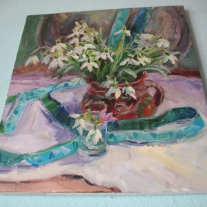 May include: An oil painting depicts a still life with white snowdrop flowers in a red ceramic pitcher and a small glass. A teal ribbon is draped across the white tablecloth. The background features muted brown tones.