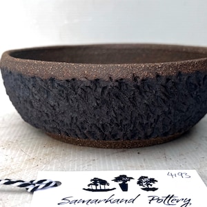 May include: A handcrafted, dark brown ceramic bowl with a textured, bark-like exterior. The rim is a lighter brown, and the interior is a darker shade. The bowl is from Samarkhand Pottery.