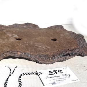May include: A rectangular, brown bonsai pot with a textured, organic design. The pot has two drainage holes and a tag with the text "Samarkand Pottery". The pot is made of ceramic and is suitable for bonsai trees.