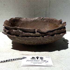 May include: Three handmade, brown pottery bowls with textured, ruffled edges, stacked to create a layered effect. A tag with "Samarkand Pottery" is attached. The bowls are likely made in Australia.