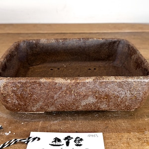 May include: A rectangular, brown ceramic bonsai pot with a textured, speckled finish. The pot features a wide, open top, slightly tapered sides, and visible drainage holes at the bottom. A small white tag with the number 4463 is placed nearby.