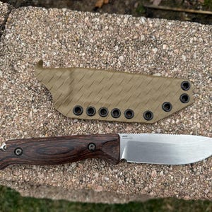 May include: A knife with a brown and black handle, a silver blade and a tan fabric sheath with black eyelets.