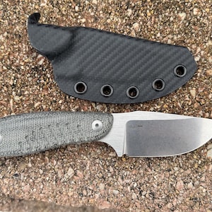 May include: A small, grey and black knife with a carbon fibre sheath. The knife has a textured handle and a plain blade.