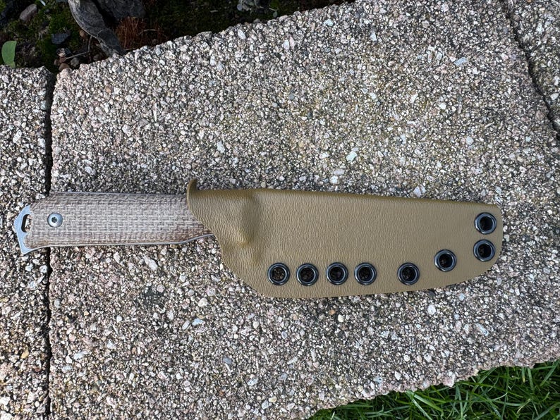 Peut inclure: Un couteau &agrave; lame fixe avec un manche beige et un &eacute;tui assorti. L'&eacute;tui comporte des &oelig;illets noirs le long du bord. Le manche du couteau a une texture tiss&eacute;e. Le couteau est con&ccedil;u pour une utilisation en ext&eacute;rieur.