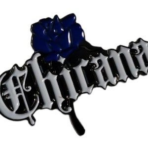 May include: A black and white enamel pin with the word "Chicana" in a stylised font. A blue rose is attached to the left side of the word.