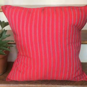 May include: Red striped throw pillow with a subtle woven texture. The pillow is made of a soft, comfortable fabric and has a classic design.
