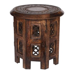 May include: A dark brown wooden side table with intricate carved details. The round top features a central oval and ornate floral patterns. The sides have carved panels with openwork designs, supported by four legs.