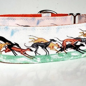 May include: A white and orange dog collar with a colourful print of greyhounds running. The collar has a silver buckle and two silver D-rings.