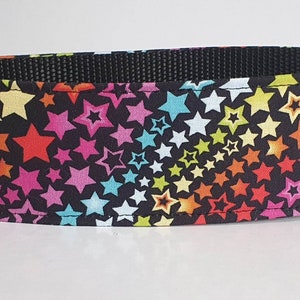 Könnte beinhalten: Ein schwarzes Hundehalsband mit einem bunten Sternenmuster. Die Sterne sind in den Farben Pink, Rot, Orange, Gelb, Grün, Blau und Lila.