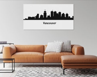 May include: A black and white canvas print featuring the Vancouver skyline. The city's silhouette is displayed against a white background, with the city name printed below. The print hangs above a brown leather sofa and ottoman.