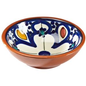 Pode incluir: Uma tigela pequena de terracota com interior branco e desenhos florais azuis, laranja e vermelhos. A tigela é perfeita para servir molhos, dips ou petiscos.