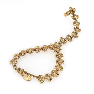 May include: Gold leaf and crystal floral design ear cuff and bracelet set. The set features a delicate chain with small leaves and crystals, and a larger leaf design at the ear cuff.