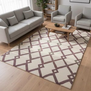 May include: A living room setting with a light grey sofa, two armchairs, and a coffee table. A cream rug with a geometric pattern in burgundy and grey tones is on the floor. The room has wooden flooring and natural light.