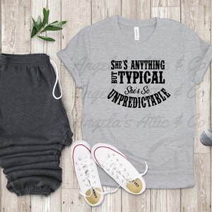 May include: Gray t-shirt with black text that reads "She's anything but typical. She's so unpredictable."