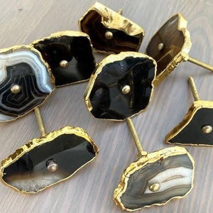 May include: Set of eight agate drawer pulls with gold trim. The agate is in various patterns of black, white, and brown.